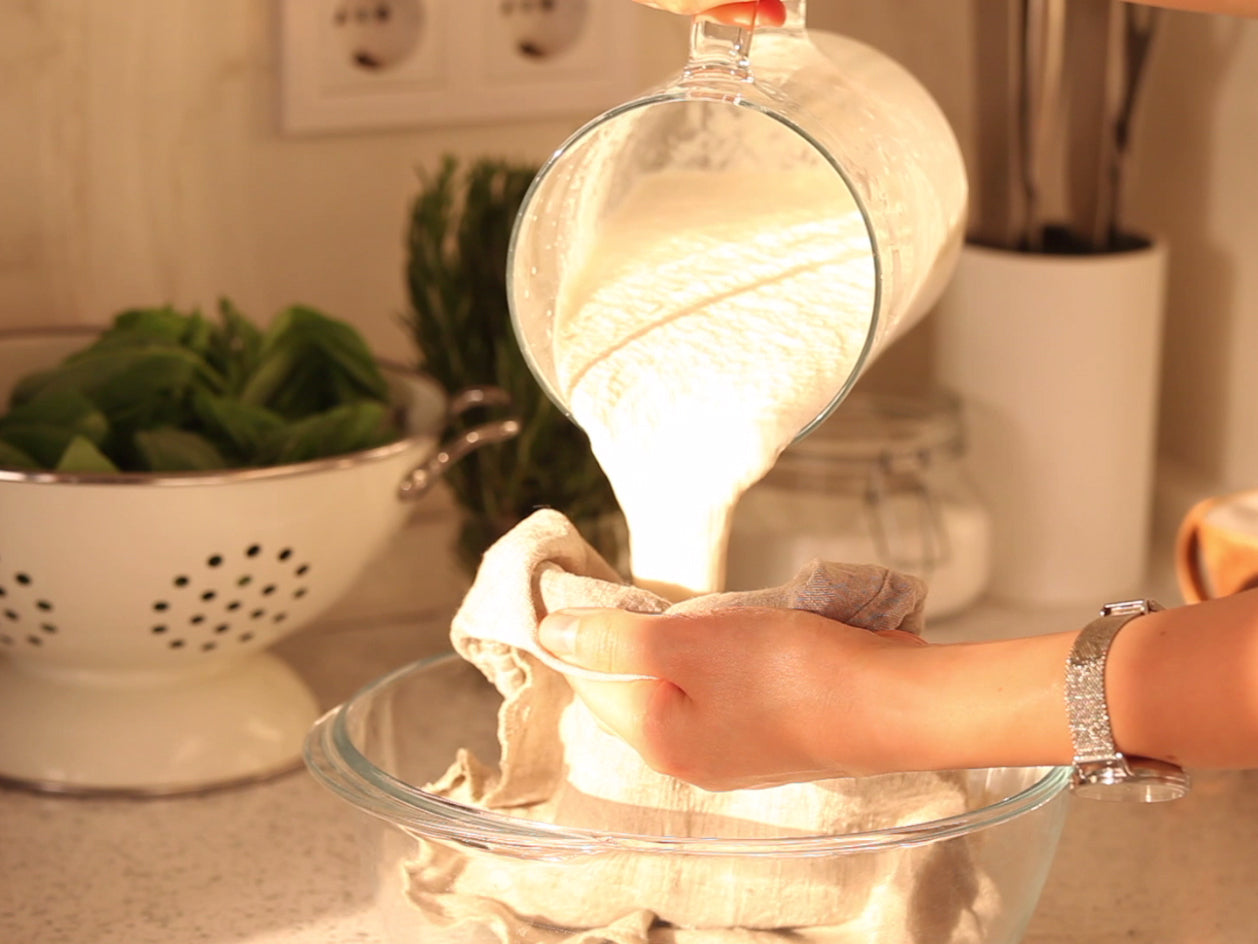 A Scene Where Almond Mash is Being Squeezed Through a Linen Nut Milk Bag.