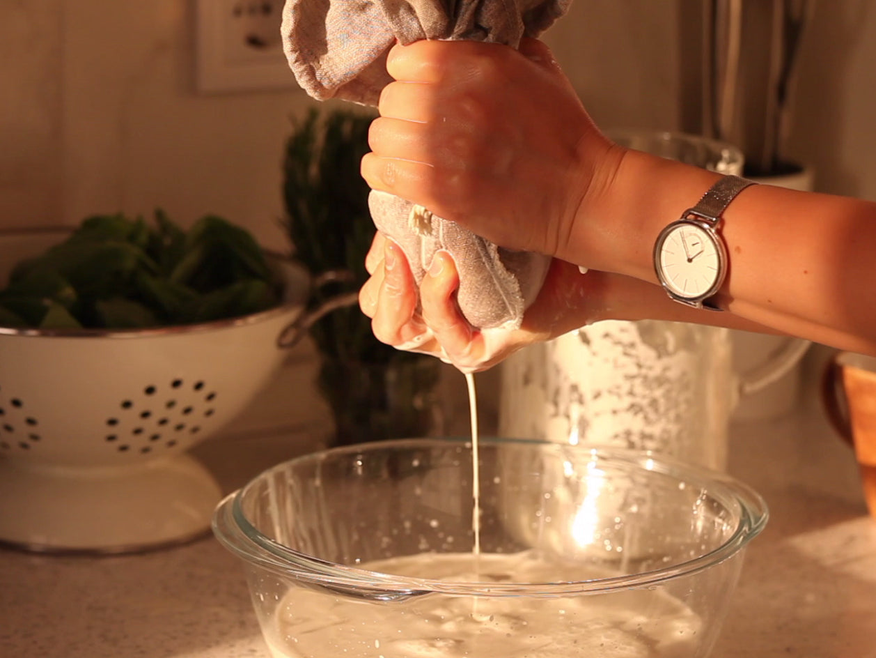 A Thin Stream of Almond Milk is Dripping Through the Linen Nut Milk Bag into a Glass Bowl.