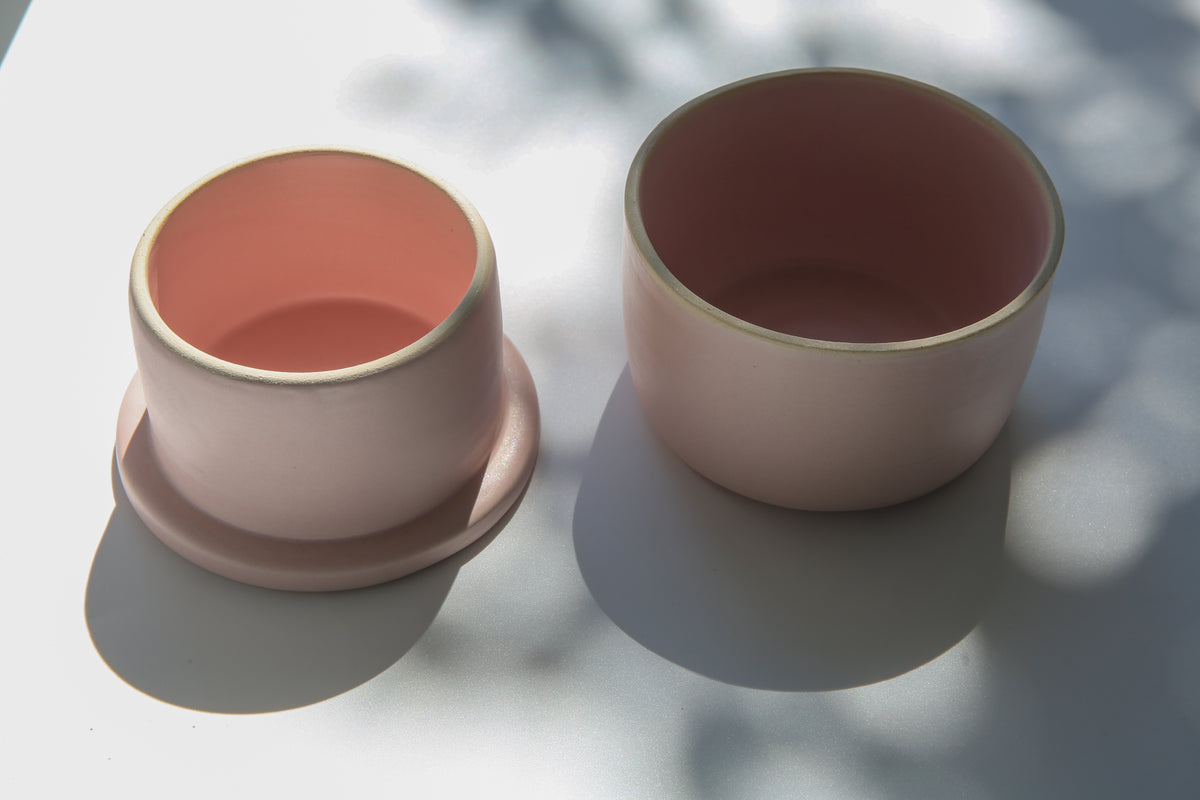 Handmade pink ceramic French butter keeper with lid, shown open in natural sunlight.