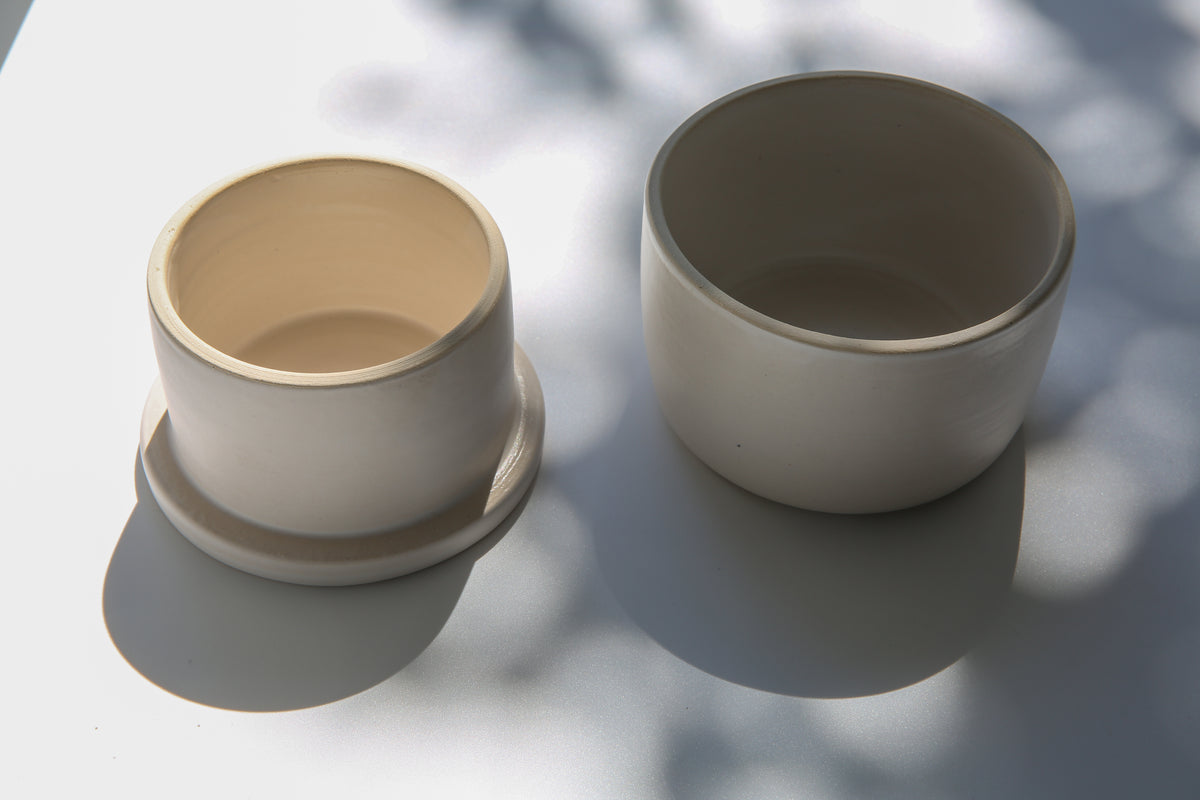 Handmade white ceramic French butter keeper with lid, shown open in natural sunlight.